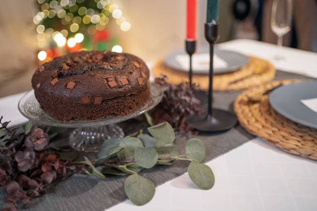Delicious chocolate cake arranged on table with candles in cozy room on background of Christmas tree with glowing garlands, Model released Copyright: xAlvaroxSanchezx MR