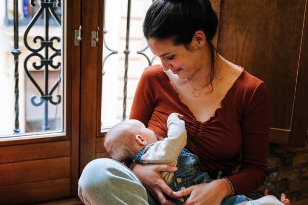IMAGO Creative: Mutterschaft Happy mother breastfeeding baby near window, Model released, Property released Copyright: xAntonioxOvejerox MR