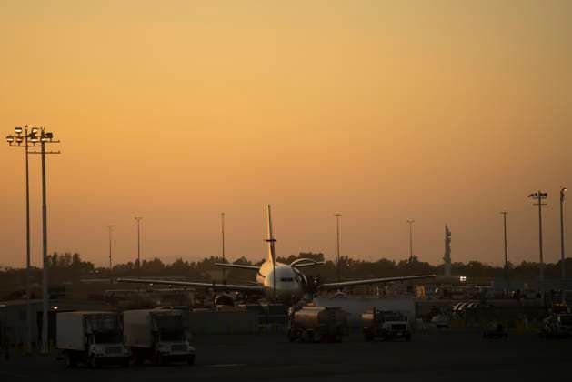 Distant shiny aircraft surrounded with service vehicles on airfield in sunset in USA, Model released Copyright: xJuanxMiguelxApariciox MR