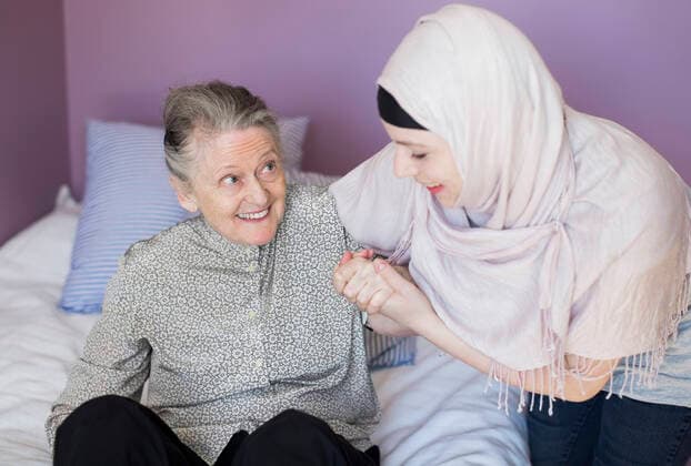 Female home caregiver assisting senior woman in bed , model released Copyright: xMaskotx , MA37413