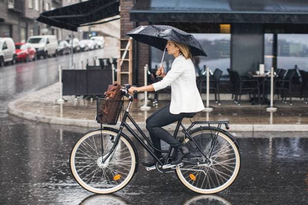 IMAGO Creative: Fit durch den Herbst Businesswoman riding bicycle on wet city street during rainy season , model released Copyright: xMaskotx , MA42348