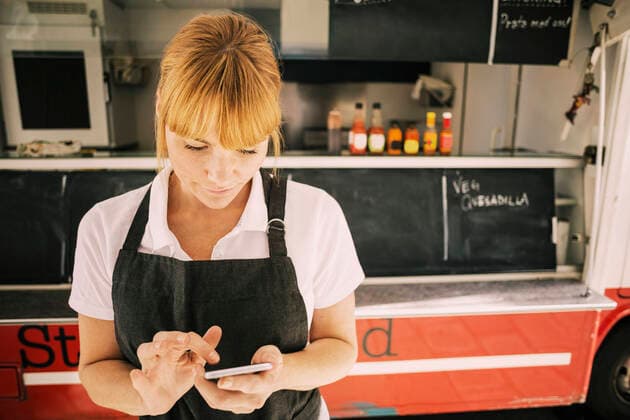 Close-up of female chef using mobile phone against food truck , model released Copyright: xMaskotx , MA48213