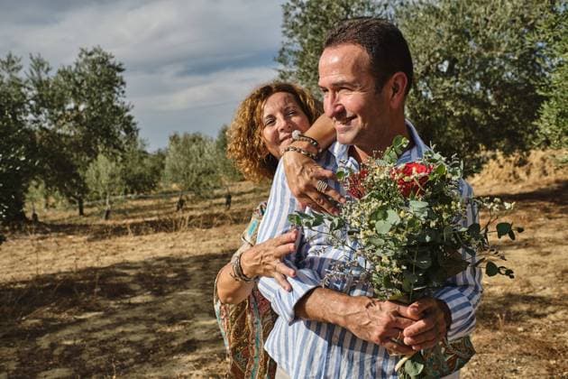 Cheerful middle aged couple in casual wear standing together with tender bouquet of flowers while enjoying stroll in summer garden on sunny day Copyright: xFatimaxGuisadox Model Released