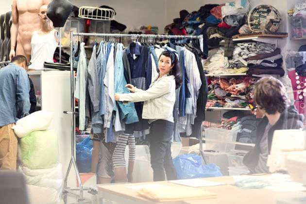IMAGO Nature: Unsere Erde, Umweltverträgliche Herausforderungen, Recycling Woman talking to volunteer while searching for clothes in rack at workshop , model released, property released Copyright: xMaskotx , MA51410