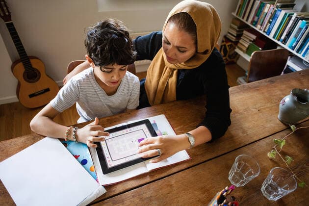 IMAGO Creative: Bildung, Musikerziehung High angle view of mother assisting son in using digital tablet while studying at home , model released, property released Copyright: xMaskotx , MA51690
