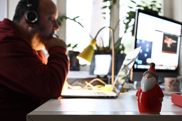 Home office man sits at home at his laptop and works At his workplace is a Santa Claus