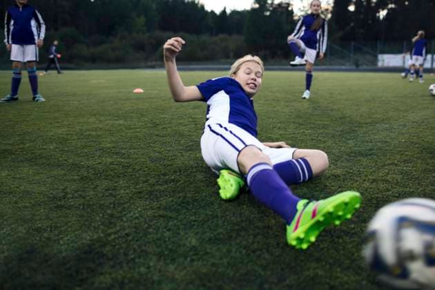 Girl sliding on grass at soccer field during training , model released Copyright: xMaskotx , MA55688