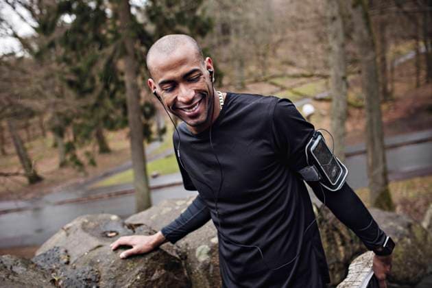 IMAGO Creative: Fit durch den Herbst Happy male athlete listening music while exercising by stone wall in forest , model released Copyright: xMaskotx , MA56663