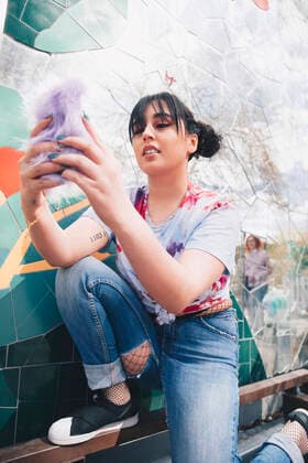 IMAGO Creative: Clickbait, Modetrends Young woman using mobile phone by mosaic wall , model released Copyright: xMaskotx , MA56722