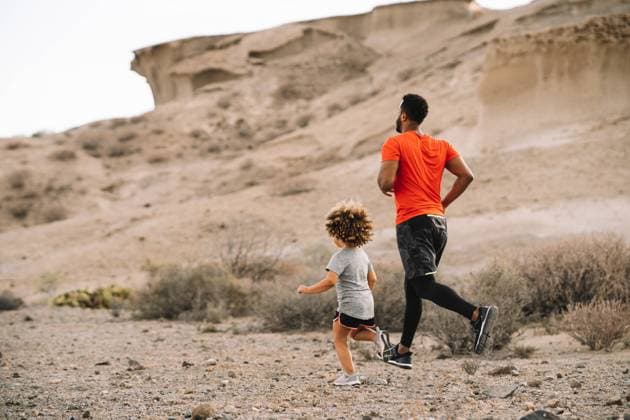 IMAGO Creative: NGO, Ausbildung f?r Kinder African American bearded active father in red t shirt running with cheerful curly child on desert landscape in backlit, Model released Copyright: xGabrielxTrujillox MR