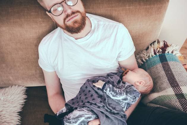 IMAGO Creative: Gesundheit, Burnout High angle view of man sleeping while holding baby boy on sofa , model released Copyright: xMaskotx , MA57378