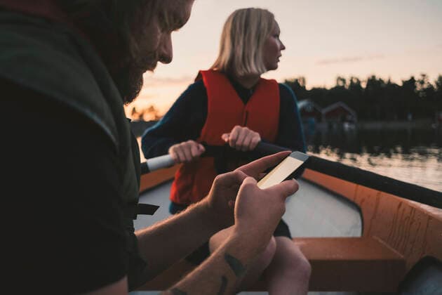 IMAGO Creative: Klimawandel - Zukunft und Innovation Man using mobile phone while woman rowing boat on lake , model released Copyright: xMaskotx , MA58781
