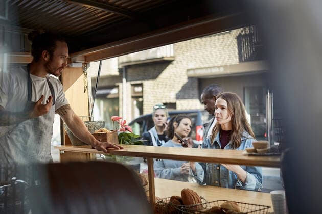 Young male owner taking order from female customer at food truck in city , model released, property released Copyright: xMaskotx , MA60445