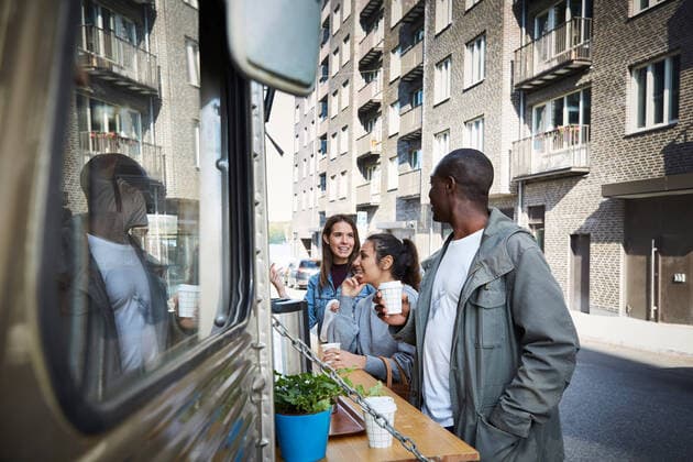 IMAGO Creative: Urban Diversity Male and female friends talking at food truck in city , model released, property released Copyright: xMaskotx , MA60465