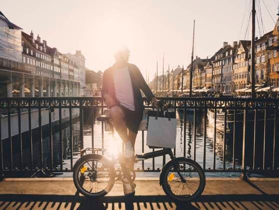 IMAGO Creative, Jahreszeit Sommer, Sommer in der Stadt Full length back lit of man standing with bicycle and shopping bags on footbridge in city , model released Copyright: xMaskotx , MA61429