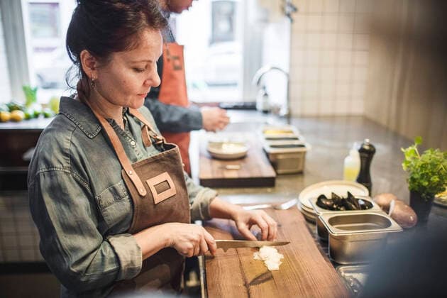 IMAGO Creative: Landleben - Essen Mature female chef cutting food on board at counter in restaurant kitchen , model released, property released Copyright: xMaskotx , MA61522