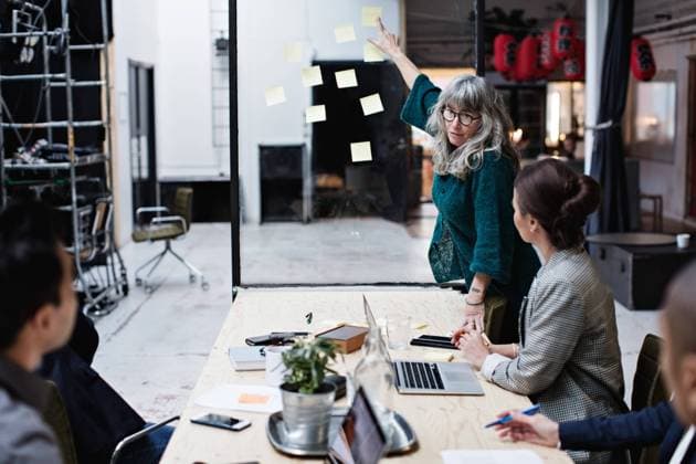 Mature businesswoman explaining adhesive notes to male and female colleagues in meeting , model released, property released Copyright: xMaskotx , MA62970