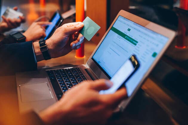 Cropped image of businessman holding credit card while using mobile phone and laptop at airport , model released, property released Copyright: xMaskotx , MA63147