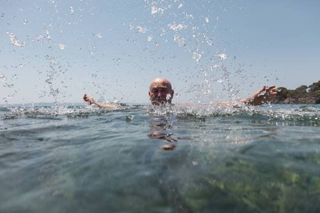 IMAGO Creative: Sommer Sport - Strand Bald mustache elderly man enjoying and splashing water looking at camera in bright sunny day in Greece Halkidiki Copyright: xInigoxCallesx Model Released