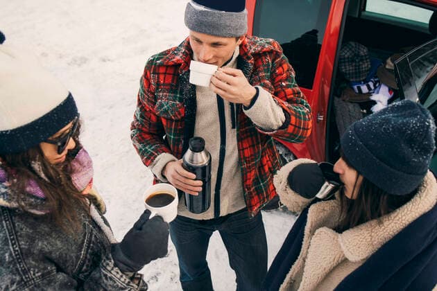 IMAGO Creative: Wintersport, Mode High angle view of friends having coffee while talking by car on snow , model released Copyright: xMaskotx , MA64146