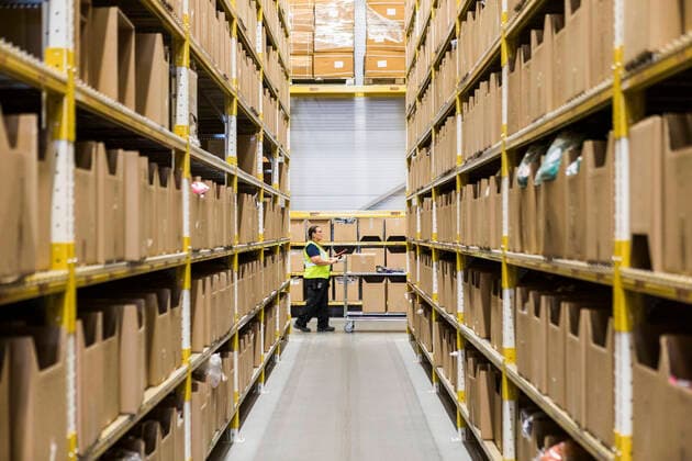 Full length side view of mature female warehouse worker pushing cart seen through narrow aisle in industrial building , model released, property released Copyright: xMaskotx , MA65219