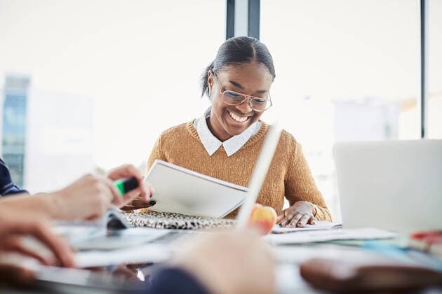 Smiling woman studying while sitting with friends at table in university cafeteria , model released, property released Copyright: xMaskotx , MA65470