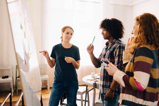 Confident businesswoman discussing project over whiteboard with technicians at creative office , model released, property released Copyright: xMaskotx , MA65778