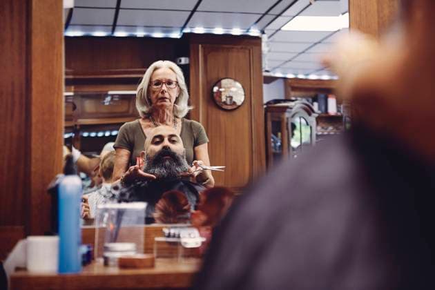 Reflection of female barber trimming beard of mid adult man in salon , model released, property released Copyright: xMaskotx , MA66993