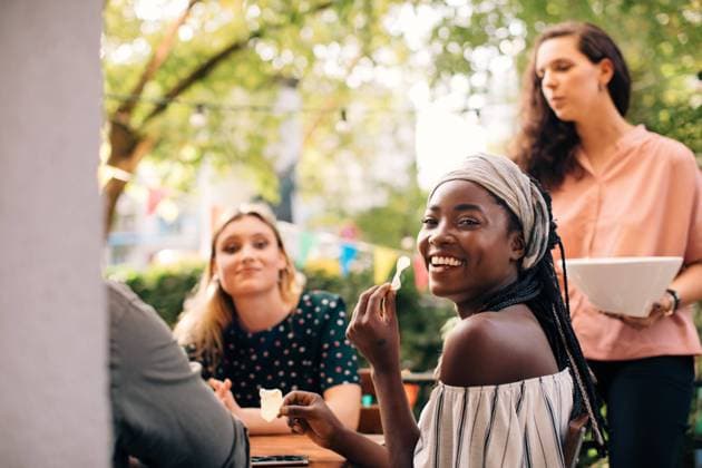 Portrait of smiling young woman eating snacks with friends in balcony , model released, property released Copyright: xMaskotx , MA68095