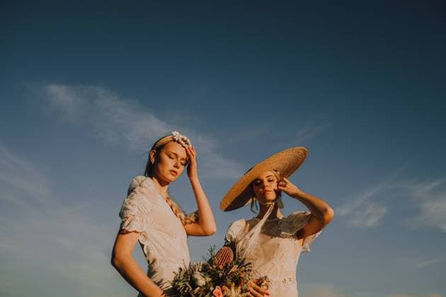 From below slim tanned women in wreath and straw hat with bunch of flowers on background of blue sky, Model released Copyright: xJakexJakabx MR