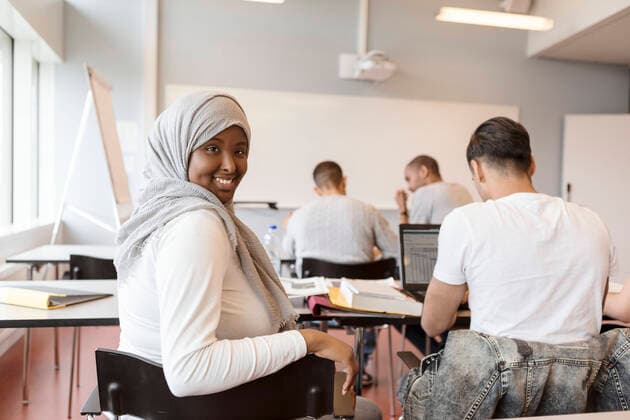 Portrait of smiling student in hijab sitting with friends in classroom at university , model released, property released Copyright: xKentarooxTrymanx , MA68383