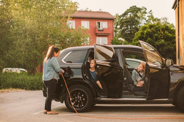 IMAGO Creative: Klimawandel - Zukunft und Innovation Girls looking at smiling mother charging electric car at station , model released Copyright: xMaskotx , MA68576