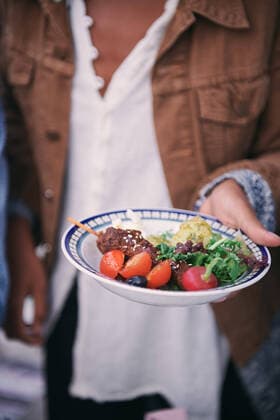 IMAGO Creative: Landleben - Essen Midsection of woman holding meal in plate during social gathering on terrace , model released, property released Copyright: xMaskotx , MA68971