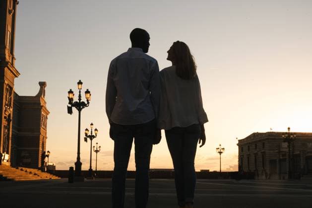 IMAGO Creative: Sommer, Abendspaziergang Back view anonymous diverse couple in casual outfits walking together along asphalt sidewalk on street during sunset time, Model released Copyright: xJakexJakabx MR