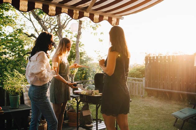 IMAGO Creative: Clickbait, Rezepte und Kochen Female friends talking while preparing food on barbecue grill in dinner party , model released, property released Copyright: xMaskotx , MA70393