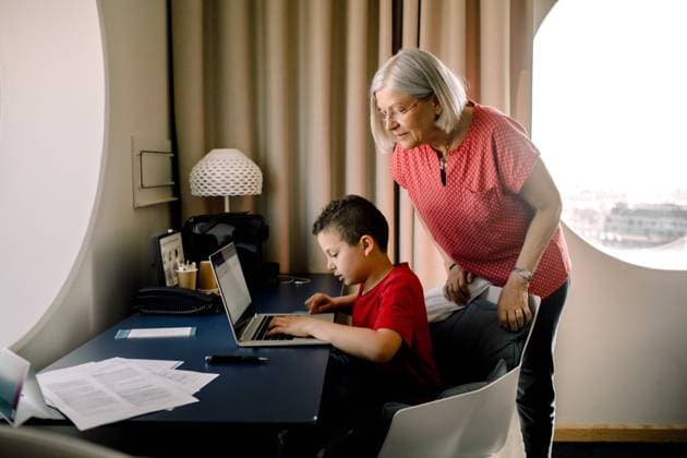 IMAGO Creative: Dichotomien, Generationen Grandmother looking at grandson using laptop while sitting by table in hotel room , model released, property released Copyright: xMaskotx , MA71610