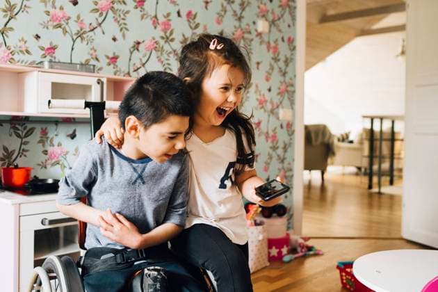 Cheerful sister watching video with autistic brother on smart phone at home , model released, property released Copyright: xMaskotx , MA72519