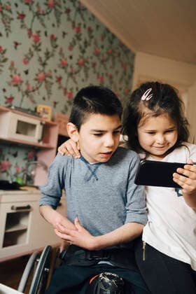 IMAGO Creative: Jahreszeit Winter, Fantasievoll drinnen spielen Sister showing video to autistic brother on smart phone at home , model released, property released Copyright: xMaskotx , MA72520