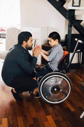 IMAGO Creative, Gesellschaft, Immer mehr Menschen haben Angst vor der Zukunft Side view of father holding autistic son s hands sitting on wheelchair at home , model released, property released Copyright: xMaskotx , MA72524