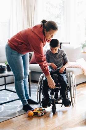 Mother assisting autistic son in sitting on motorized wheelchair at home , model released, property released Copyright: xMaskotx , MA72528