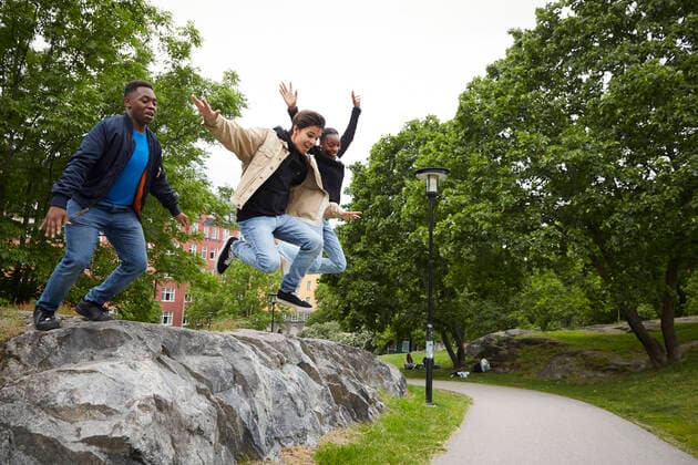 Full length of friends jumping on footpath from rock at park , model released Copyright: xMaskotx , MA73727