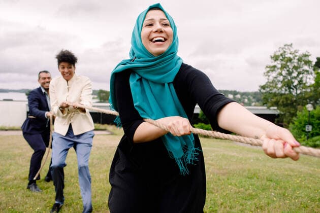 Smiling multi-ethnic male and female colleagues pulling rope while playing tug-of-war in lawn , model released, property released Copyright: xMaskotx , MA73817