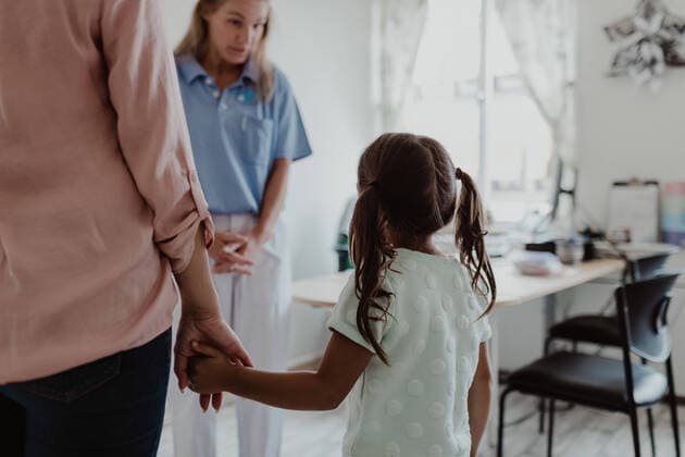 IMAGO Creative: Lokalhelden - Gesundheits- und Rettungskräfte Girl holding hands of mother while female pediatrician explaining in doctor s office , model released, property released Copyright: xMaskotx , MA73973