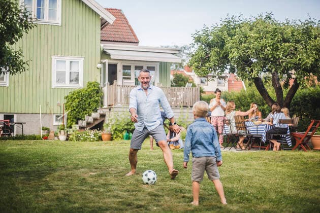 IMAGO Creative: Vaterschaft Father playing football with son while friends having fun at table in backyard party , model released, property released Copyright: xMaskotx , MA74065