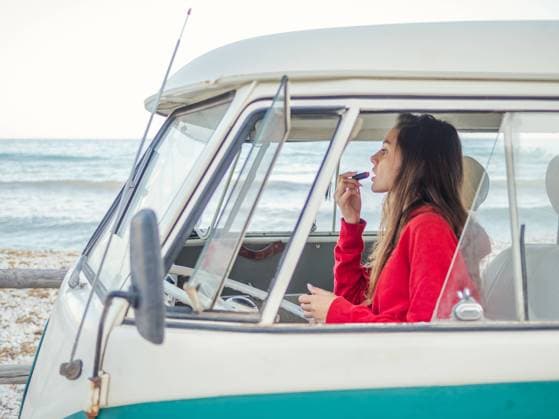 Side view of young woman coloring lips sitting in front seat of car at seaside Copyright: xJavierxDexLaxTorrex Model Released