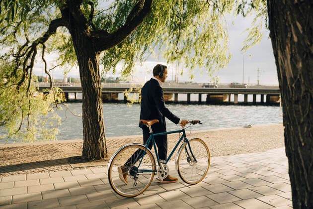 Businessman walking with bicycle on footpath in city , model released Copyright: xMaskotx , MA74460