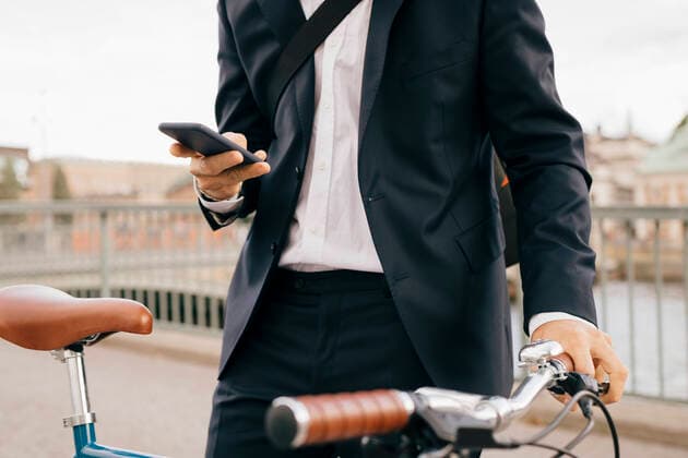 IMAGO Creative: Corporate: Klimaschutz, Digitalisierung und Urbanisierung Midsection of businessman using smart phone while standing with bicycle on bridge in city , model released Copyright: xMaskotx , MA74489