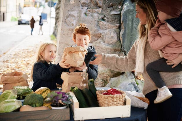 Smiling male and female sibling buying vegetables from female market vendor , model released Copyright: xMaskotx , MA77096