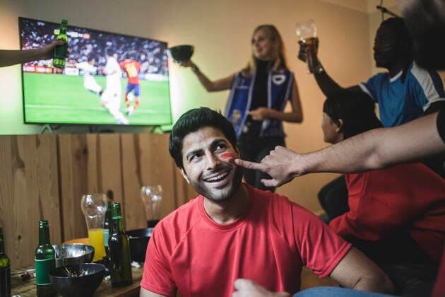 Cropped hand of man applying face paint on friend s cheek during soccer match , model released, property released Copyright: xMaskotx , MA77369