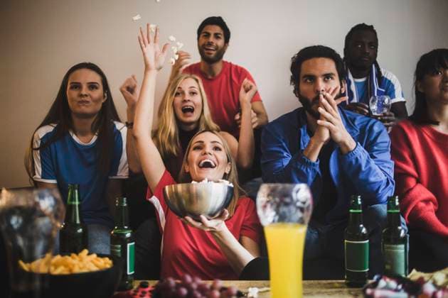 IMAGO Creative, Lifestyle, Leben in einer Wohngemeinschaft, WG Male and female soccer fans watching match while sitting on sofa at home , model released, property released Copyright: xMaskotx , MA77407